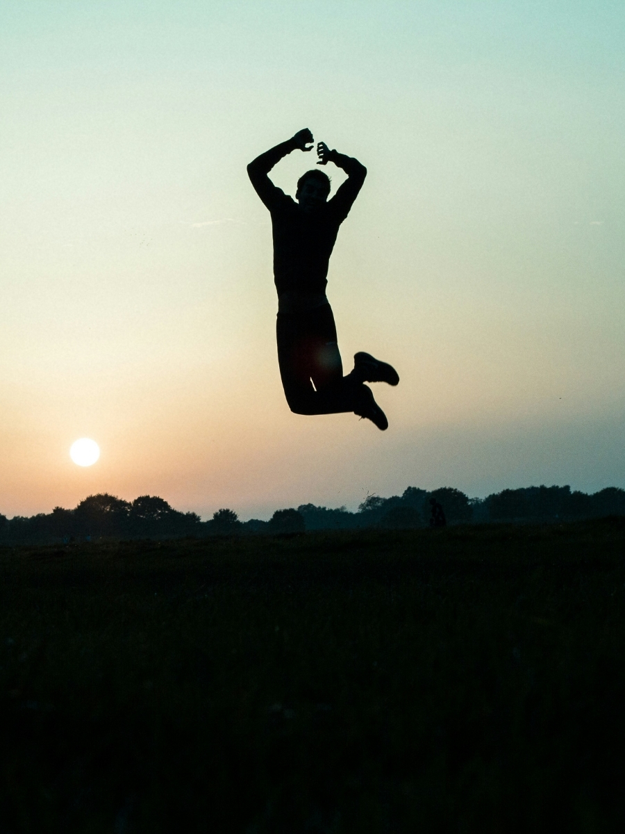 Silhouette d'une personne sautant de joie au coucher du soleil